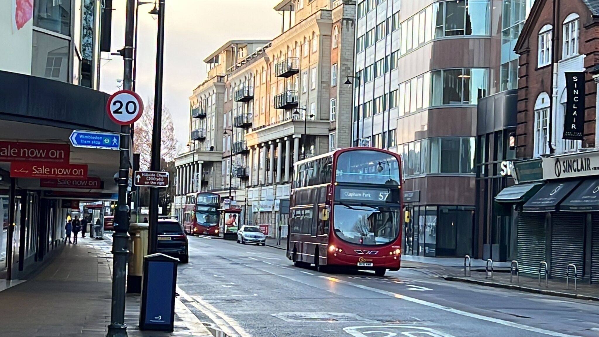En gata med en röd dubbeldäckarbuss, byggnader och en skylt som visar hastighetsbegränsningen.