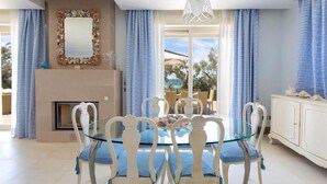 A dining area with a glass table and white chairs, a fireplace, and a view of the outdoors. - 481 Villa di Lusso Sulla Spiaggia a Porto Cesareo (Porto Cesareo)