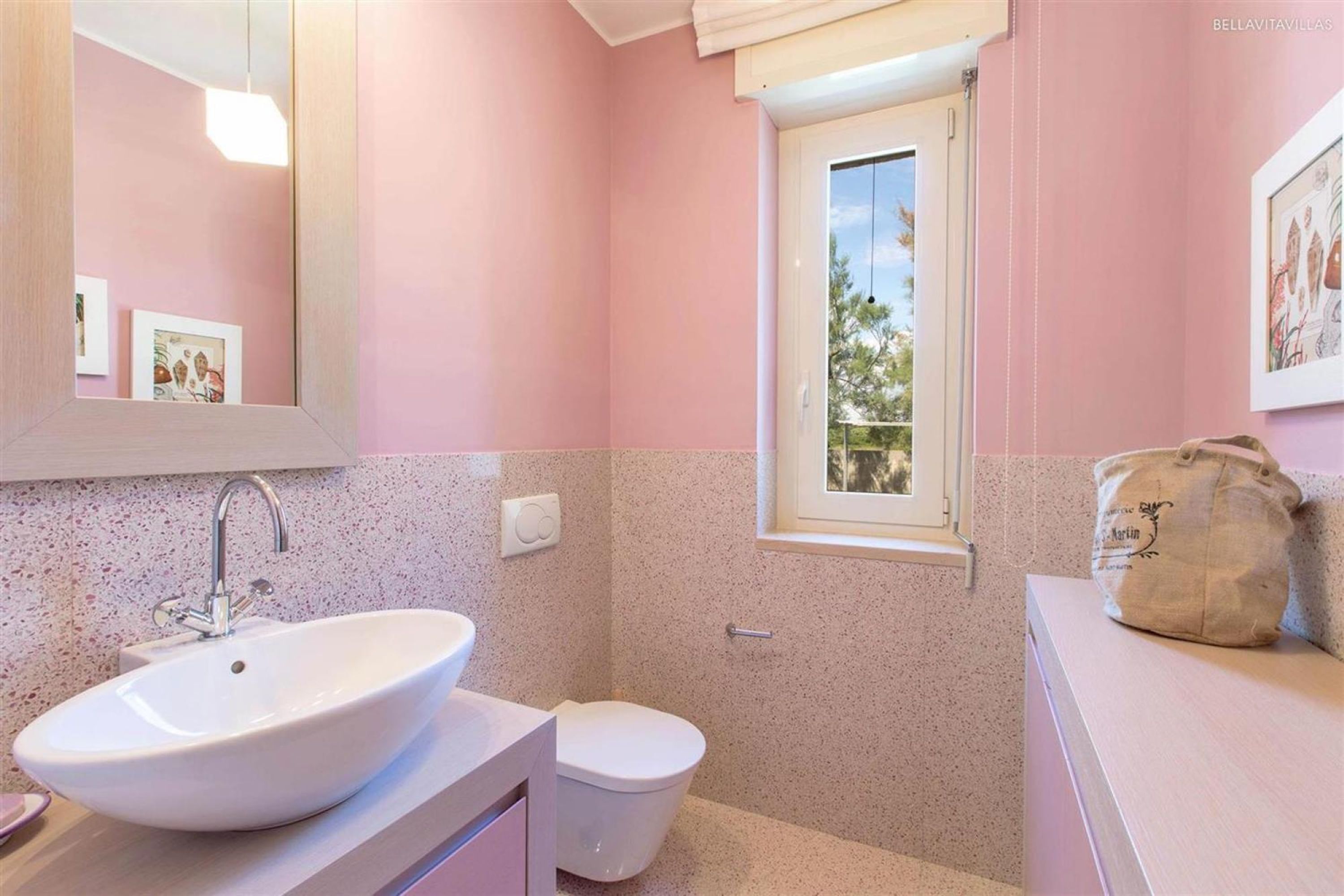 A bathroom with a white sink, a toilet, a window, and a mirror.
