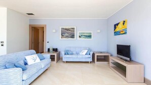 A living room with two sofas, a TV, artwork on the wall, and a door. - 481 Villa di Lusso Sulla Spiaggia a Porto Cesareo (Porto Cesareo)