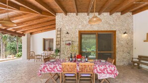 A stone-walled room with a wooden ceiling, a dining table set for two, and a large window. - 425 Casa in Campagna con Piscina a San Donaci (San Donaci)