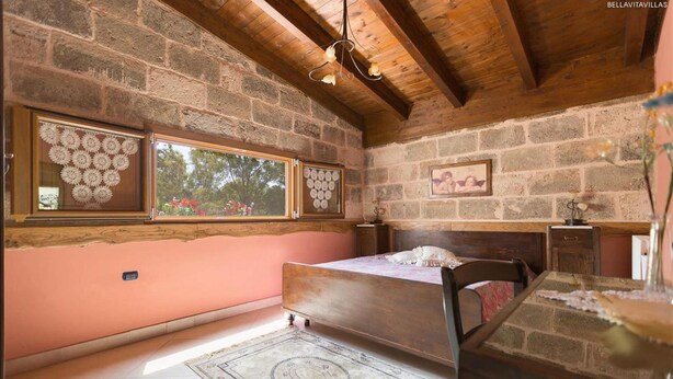 A bedroom with a wooden ceiling, a bed, a window with lace curtains, a picture on the wall, and a bedside table. - 425 Casa in Campagna con Piscina a San Donaci (San Donaci)