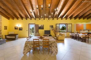 A spacious living area with a dining table, sofas, and a kitchen in the background. - 425 Casa in Campagna con Piscina a San Donaci (San Donaci)