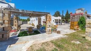 A courtyard with stone walls, outdoor seating, and a pergola. - 1643 Tenuta Fioravante - Bilo Nettuno (Porto Cesareo)