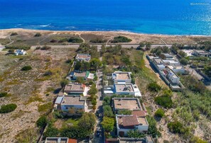 An aerial view of a coastal residential area with houses arranged in rows, a beach in the background, and a clear sky. - 1687 Villa Blu Cobalto - Appartamento 1 (Manduria)