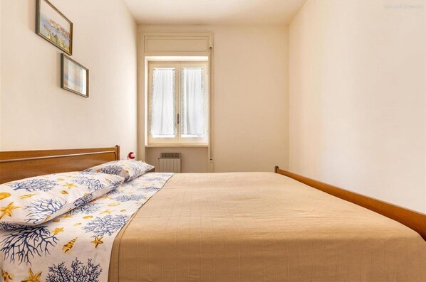 A bedroom with a bed, a window, and two framed pictures on the wall.