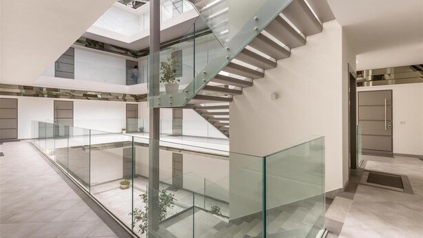 A modern interior with a glass staircase connecting two floors, a central atrium with plants, and a minimalist design. - 1937 Bella Vita Appartamento Simone (Gallipoli)