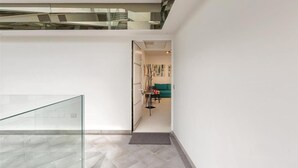 A modern interior with a glass railing, a staircase, and a living area with artwork and a sofa. - 1937 Bella Vita Appartamento Simone (Gallipoli)