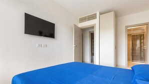 A modern hotel room with a large bed, a flat-screen TV mounted on the wall, and a walk-in closet. - 1937 Bella Vita Appartamento Simone (Gallipoli)