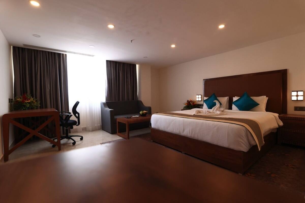 Una habitación de hotel con una cama grande, un escritorio, una silla y un televisor.