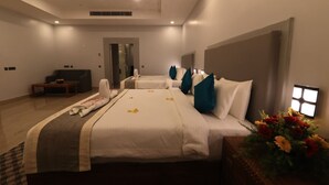 A hotel room with two beds, a sofa, a small table, and a flower arrangement. - Seven Hills Hotels (Puri)