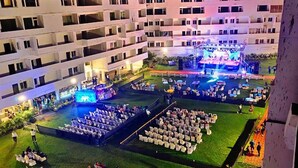 A hotel courtyard with a stage for events, seating areas, and a pool. - Seven Hills Hotels (Puri)