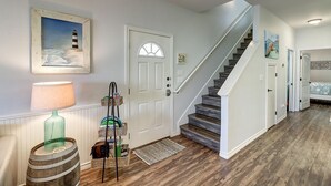 A staircase with wooden steps and white walls, leading to a bedroom with a bed and a painting. - New Listing: Peach Paradise (Port Aransas)