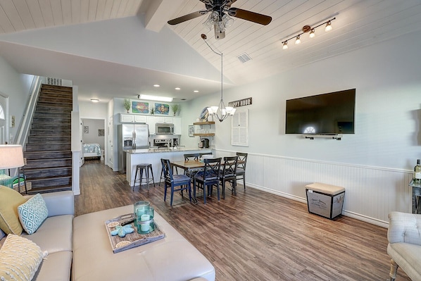 A spacious living area with a kitchen, dining table, and a staircase leading to another level.