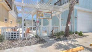 A beachfront property with a covered patio, pool area, and a sign for Pelican's Roost. - New Listing: Peach Paradise (Port Aransas)
