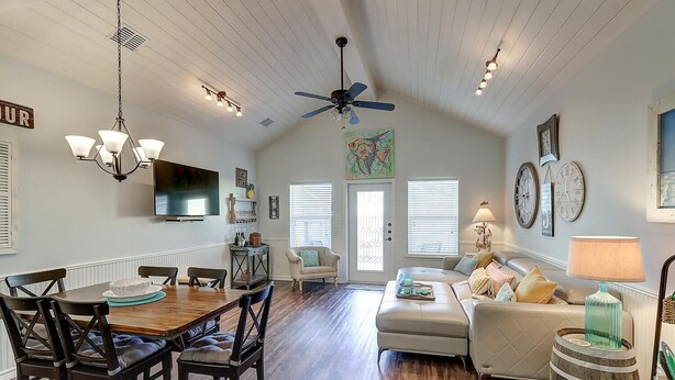A spacious living area with a wooden dining table, a sofa, and a ceiling fan. - New Listing: Peach Paradise (Port Aransas)