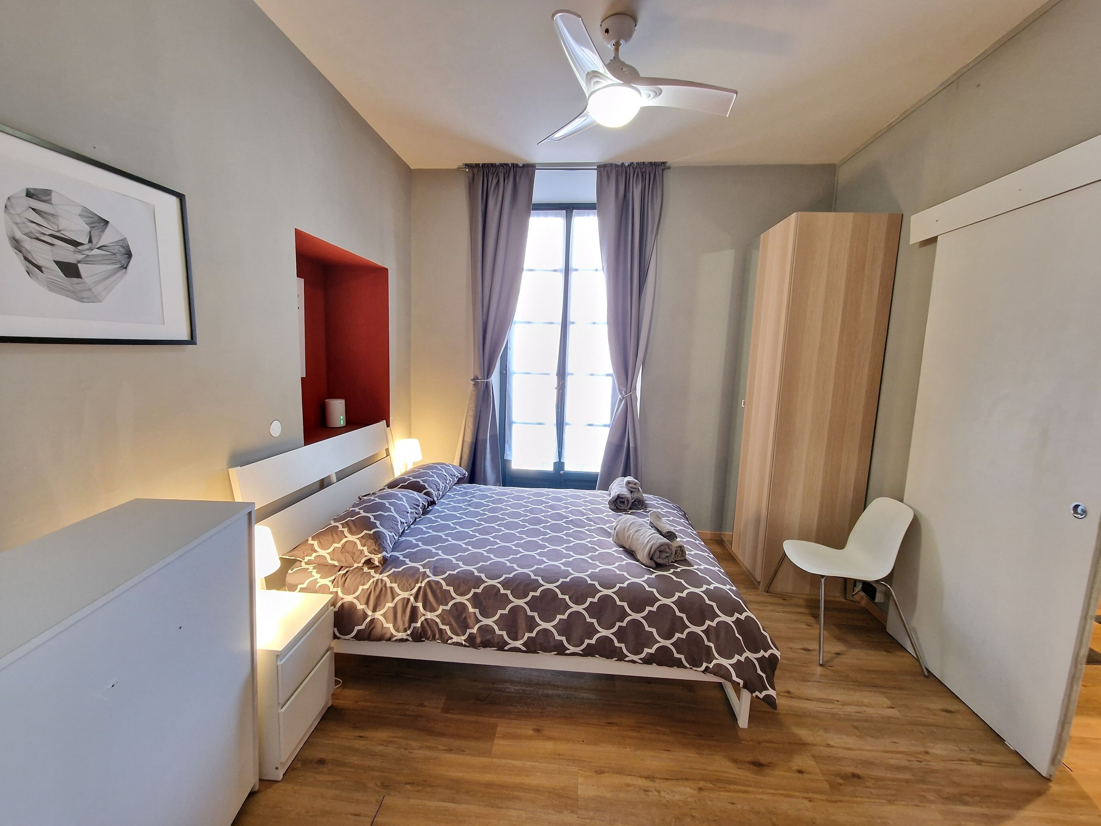 Un dormitorio moderno con cama, mesita de noche y ventilador de techo.