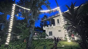 A house with a white exterior, surrounded by greenery and palm trees. - Home in Varkala (Varkala)