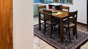 A dining area with a wooden table and chairs, a black pendant light, and a patterned rug. - Home in Varkala (Varkala)