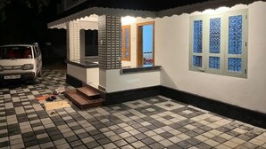 A small house with a tiled porch, a vehicle parked outside, and a window with a decorative pattern. - Home in Varkala (Varkala)
