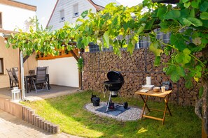 A backyard with a barbecue grill, a table with plates and a candle, and a stone wall.
