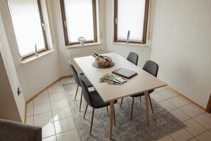 Enjoy meals and meetings in this stylish dining area with a table for four, comfortable chairs, and a decorative plant.