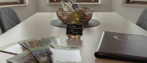 Una mesa con una cesta de mimbre que contiene botellas, un letrero con un corazón y un libro encuadernado en cuero.