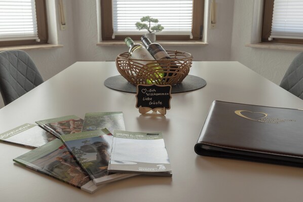 A table with a wicker basket containing bottles, a sign with a heart, and a leather-bound book.