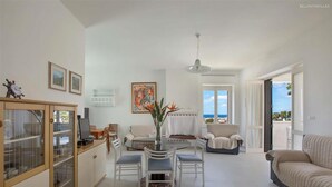 A spacious living area with a dining table, chairs, a sofa, and a view of the sea. - 674 Villetta con Vista Mare a Santa Maria al Bagno (Nardò)