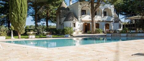 A large, white, castle-like building with a swimming pool in front.