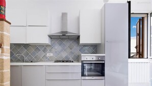A modern kitchen with white cabinets, a gas stove, an oven, and a tiled backsplash. - 857 Appartamento Sirena (Porto Cesareo)