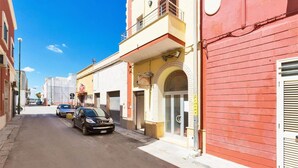 A narrow street lined with buildings, including a red brick building with a sign that reads "BELLAVITAVILLAS". - 857 Appartamento Sirena (Porto Cesareo)