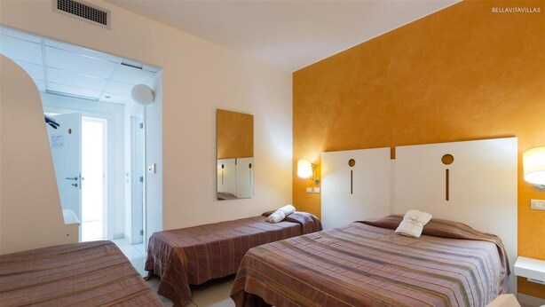 Quarto de hotel com duas camas de solteiro, banheiro e vista para o exterior.