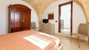 Ein Schlafzimmer mit Bett, Kleiderschrank, Fernseher und Balkon.