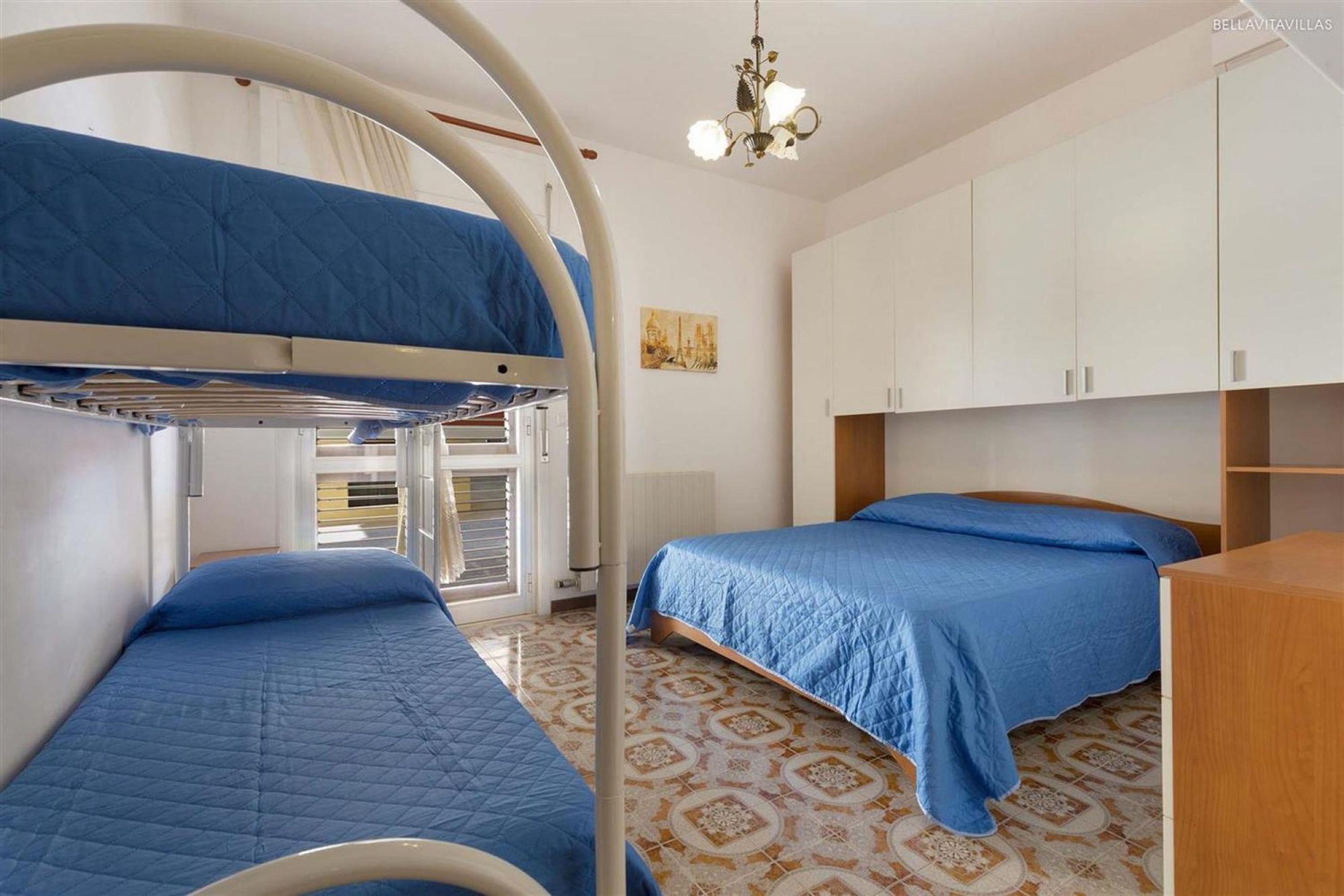 A room with bunk beds, a chandelier, and patterned flooring.