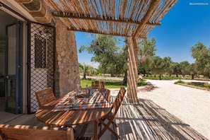 An outdoor dining area with a table and chairs, a pergola, and a view of trees and a gravel path. - 372 Pajara con Piscina a Casarano Gallipoli (Casarano)