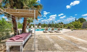 A poolside area with lounge chairs, a wooden pergola, and a bed with a pink cushion. - 372 Pajara con Piscina a Casarano Gallipoli (Casarano)