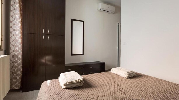 A bedroom with a bed, a wardrobe, a mirror, and an air conditioning unit. - 1299 Versomare - Monolocale Lu Mare (Porto Cesareo)