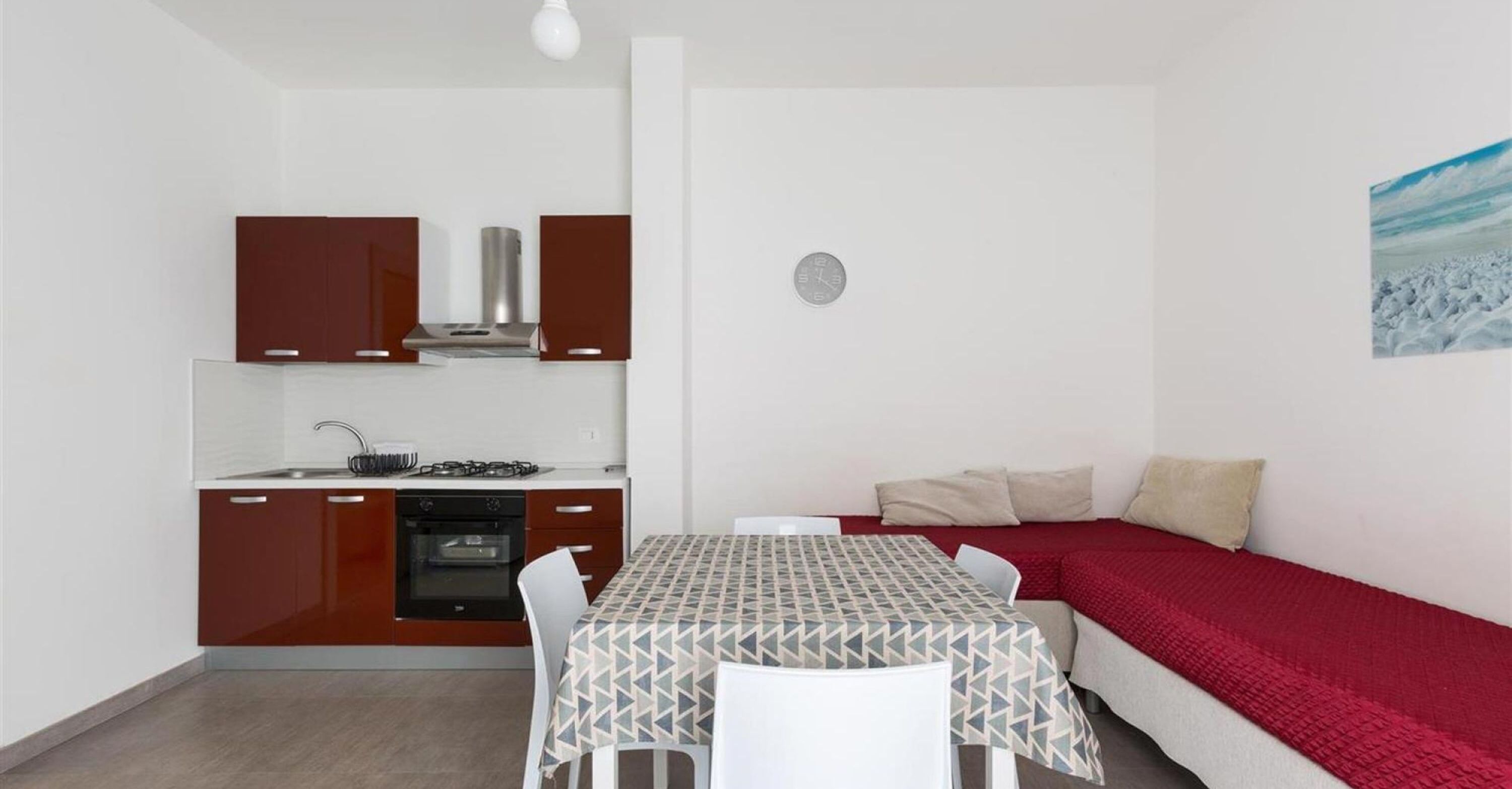 A compact living space with a kitchenette, a dining table, and a sofa.