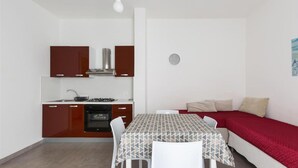 A compact living space with a kitchenette, a dining table, and a sofa. - 1299 Versomare - Monolocale Lu Mare (Porto Cesareo)