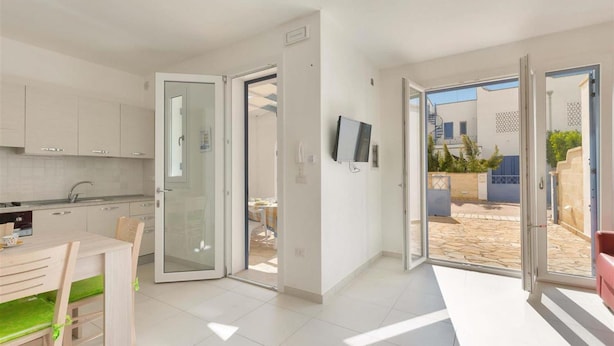 A modern apartment with a kitchen, dining area, and a balcony with a view of the outside. - 1514 Villetta Michela (Nardò)