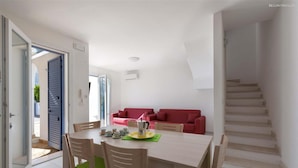 A dining area with a table and chairs, a red sofa, and a staircase. - 1514 Villetta Michela (Nardò)