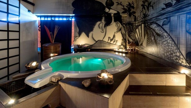 A spa area with a hot tub, decorative stones, and a mural on the wall. - 1743 Silver Hotel - Singola Business (Matino)