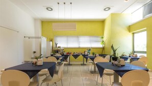 A dining area with tables and chairs, a large window, and a yellow wall. - 1743 Silver Hotel - Singola Business (Matino)