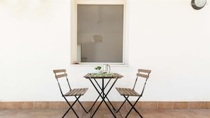 A small outdoor table with two chairs, a window above, and a tiled floor. - 2028 Soledelsud - Monolocale by Barbarhouse (Otranto)