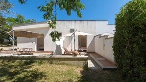 A modern outdoor patio area with a white building, two umbrellas, a table, and chairs. - 2028 Soledelsud - Monolocale by Barbarhouse (Otranto)