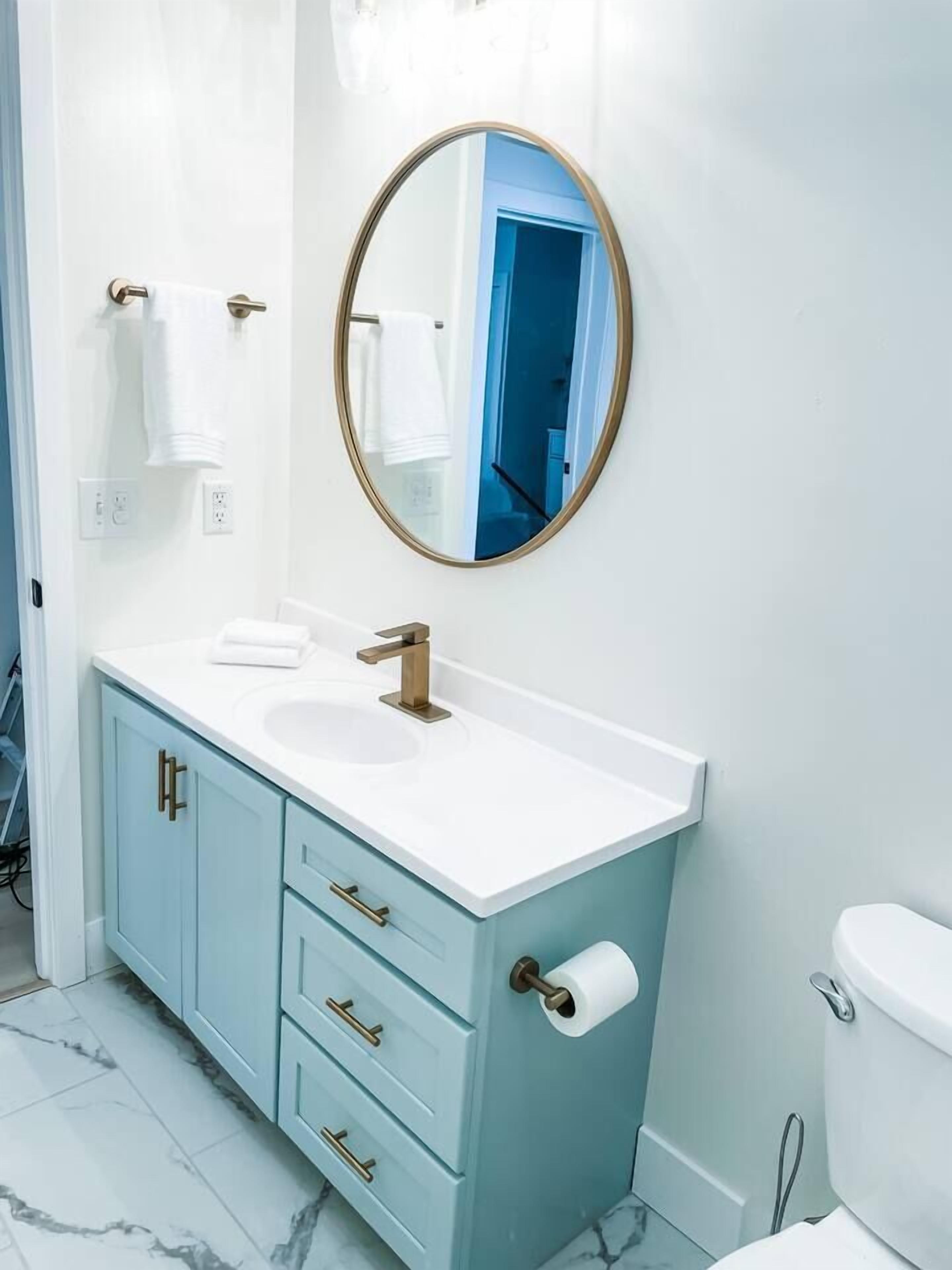 Un baño con lavamanos blanco, grifo dorado y muebles de color azul claro.