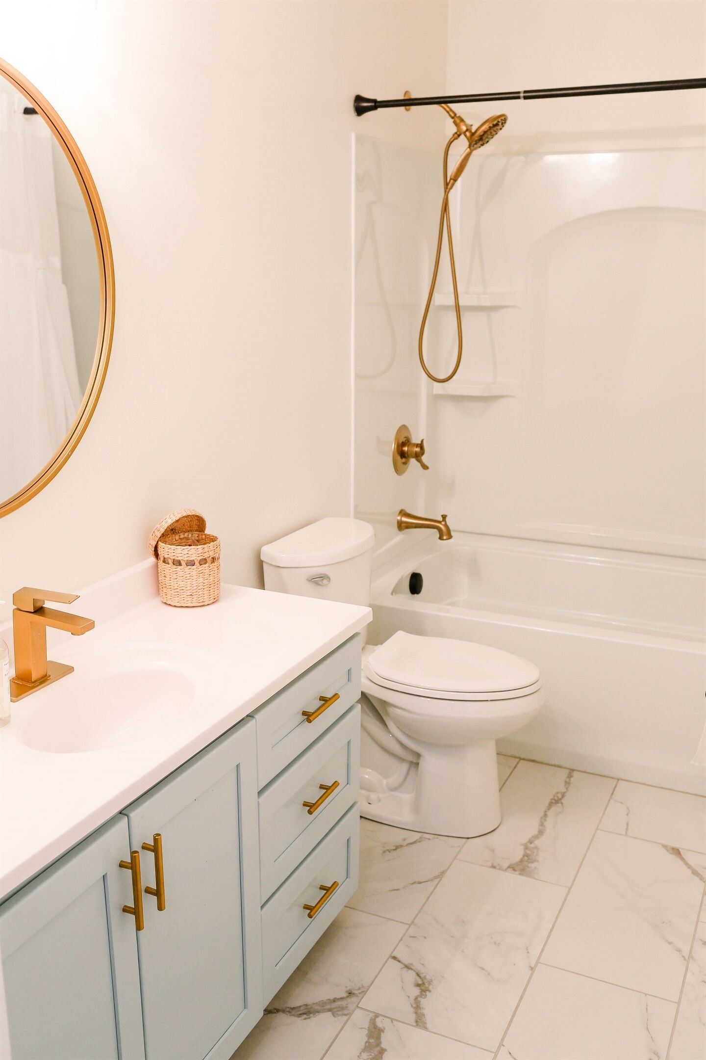 Un baño con lavamanos blanco, detalles dorados, inodoro y bañera con ducha.
