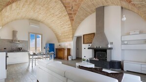A spacious living area with a high arched ceiling, a fireplace, and a modern kitchen. - 777 Rifinita Villa con Piscina a Presicce (Presicce-Acquarica)
