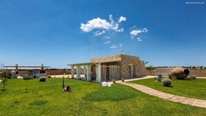 A modern villa with a stone facade, a covered patio, and a well-maintained lawn. - 777 Rifinita Villa con Piscina a Presicce (Presicce-Acquarica)